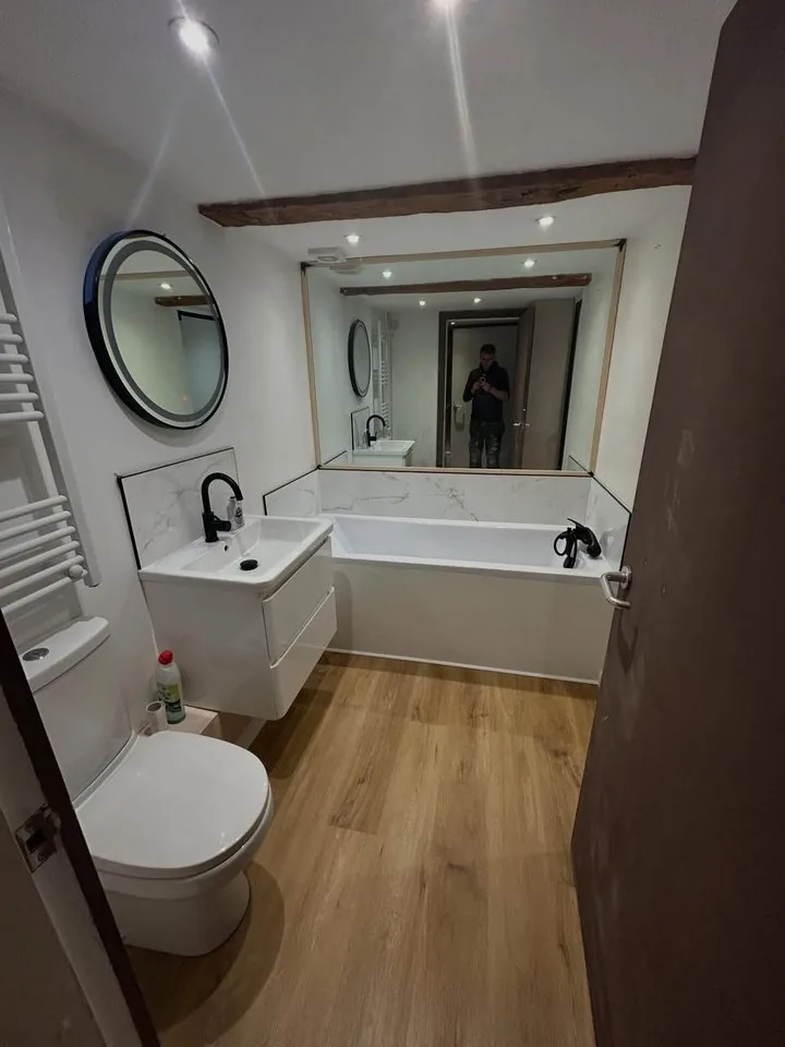 Finished bathroom with wood-effect floor, vanity unit and round mirror