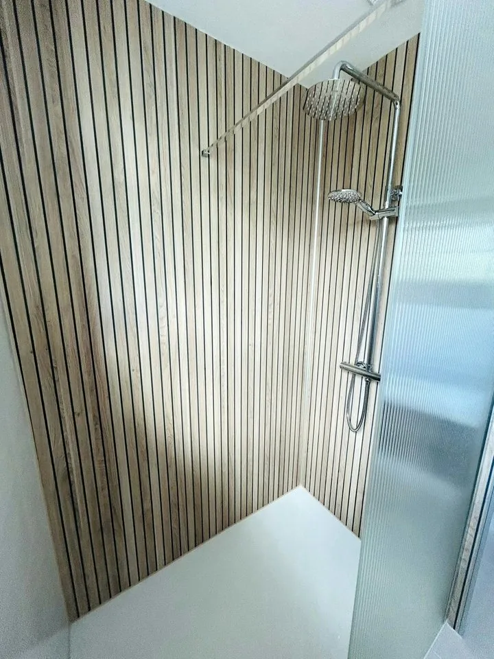 Walk-in shower with slatted wall panels and a glass screen