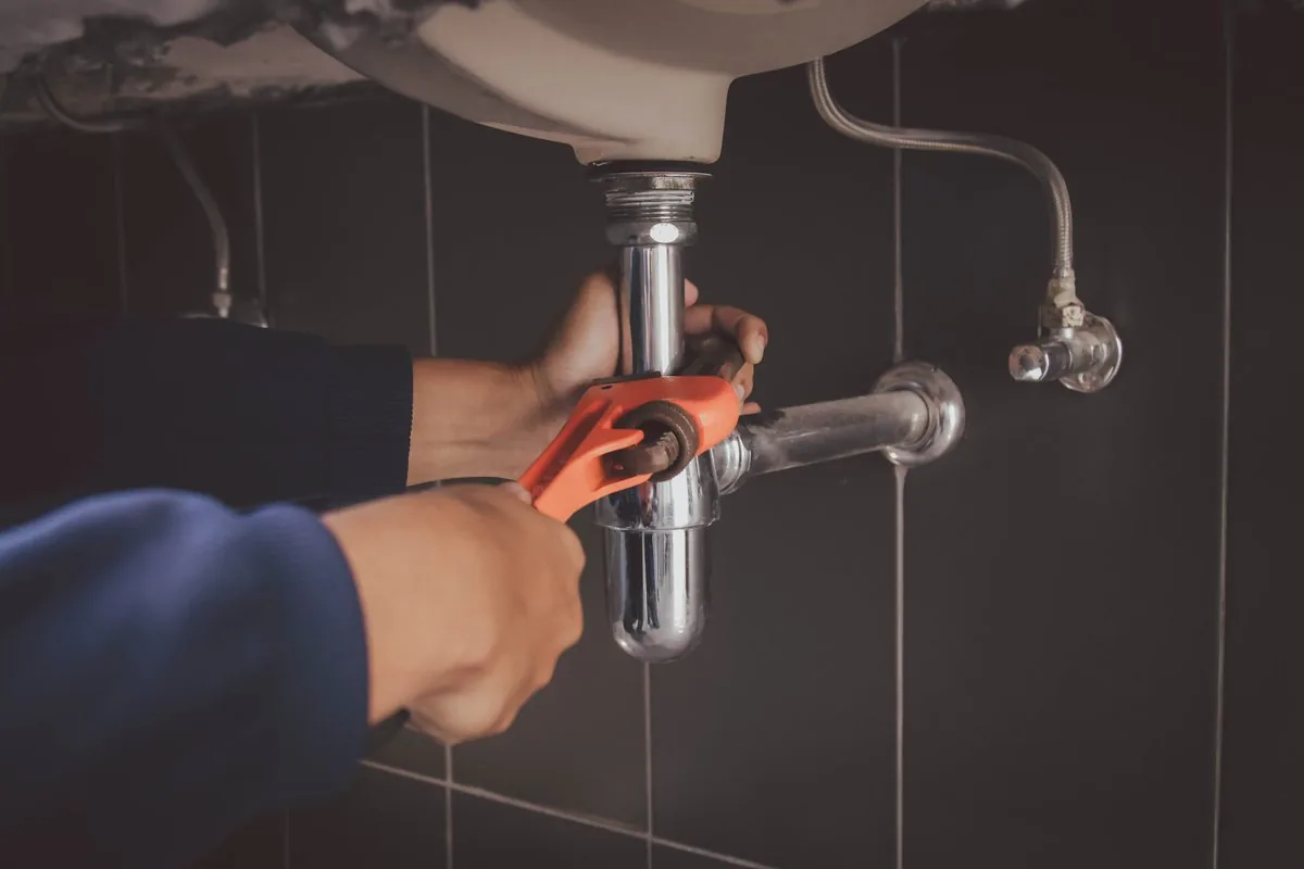 Hands tightening a basin waste pipe with grips
