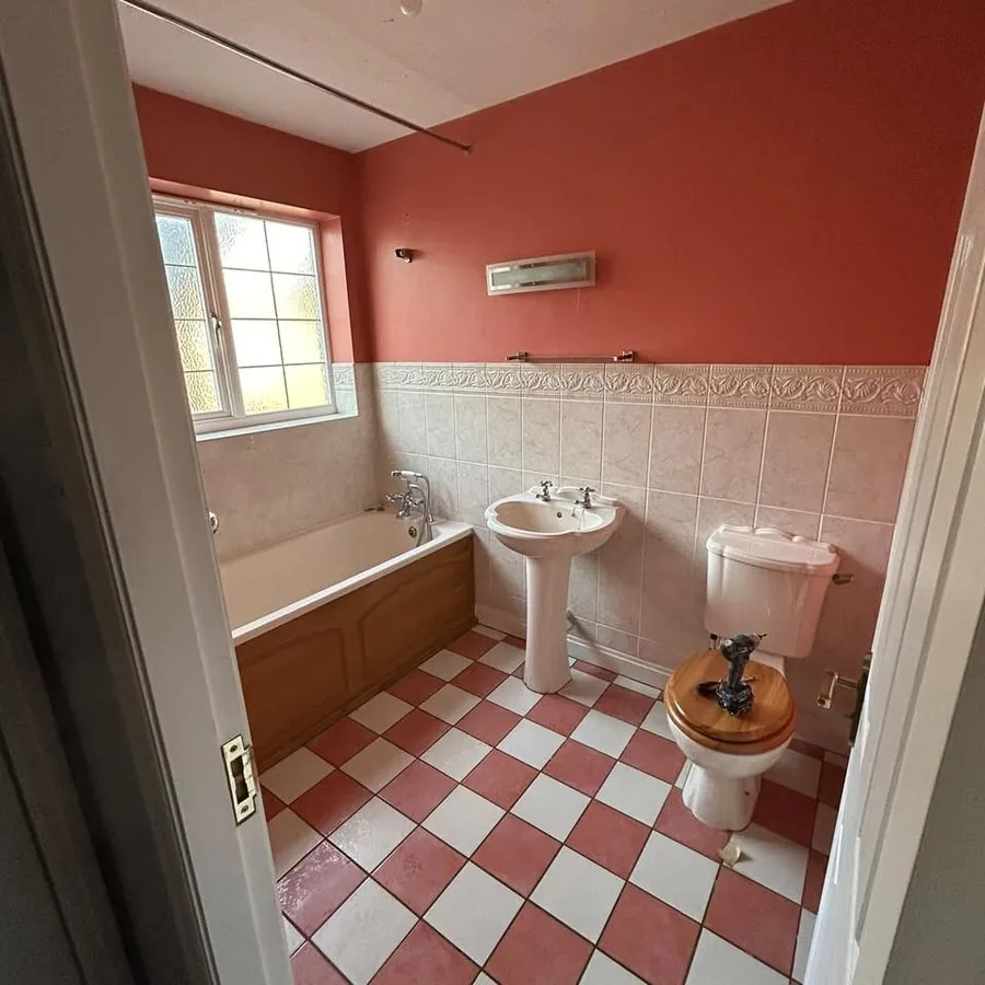 Before: a dated bathroom with red and white floor tiles